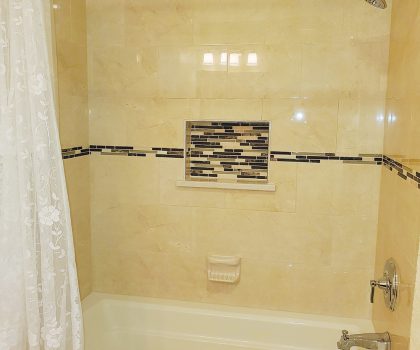 Acclaim Renovations & Design transformed this outdated bathroom by adding quartz tile and a functional niche